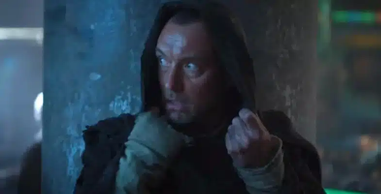 Jod, de la série Skeleton Crew, vêtu d'une cape avec la capuche relevée, regardant attentivement autour de lui.