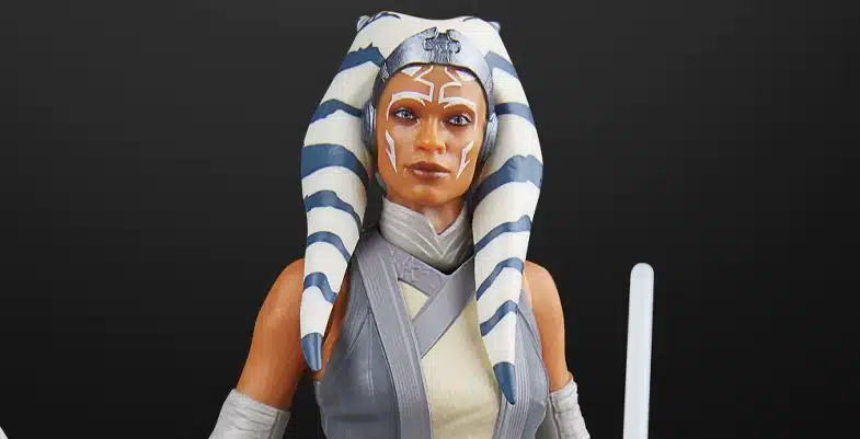 Figurine d'Ahsoka Tano, un personnage de l'univers de Star Wars, avec des marques faciales distinctives et des lekku bleus et blancs, tenant deux sabres laser.