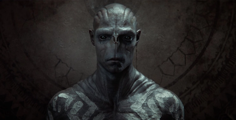 Un batteur regarde la caméra. Il a un visage alien frappant.