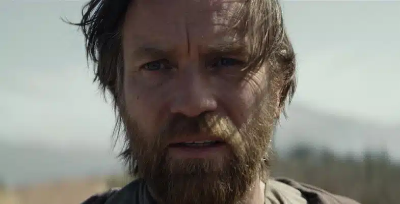 Portrait rapproché d'Obi-Wan Kenobi avec une expression sérieuse, les cheveux en bataille et une barbe, regardant au loin